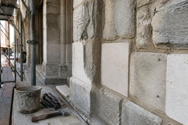 Historic stone facade restoration with matched replacement stone, repointed mortar joints, and masonry tools in Birmingham, Alabama.
