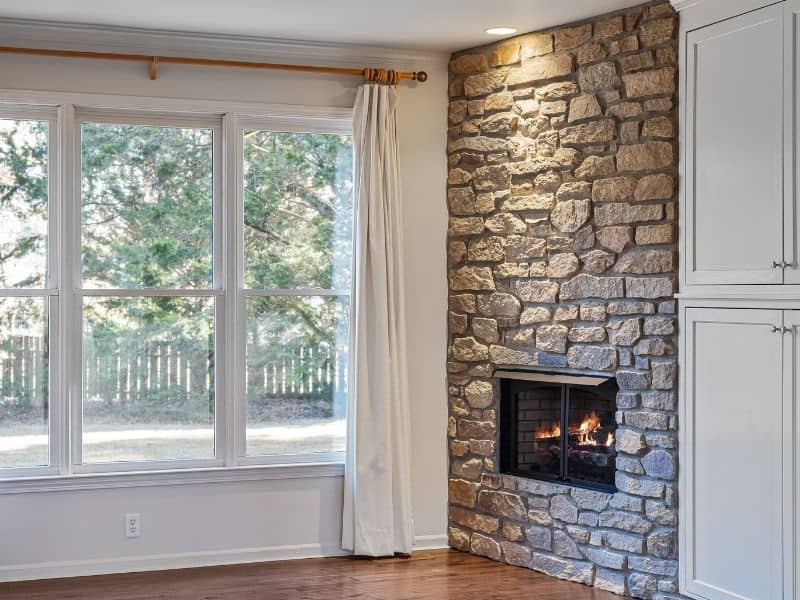 Stone fireplace meeting a hardwood floor, showing the hearth-to-floor transition