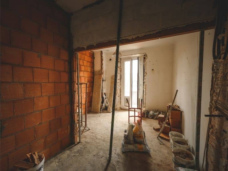 Partially renovated interior with exposed brick walls, illustrating work involving painted brick