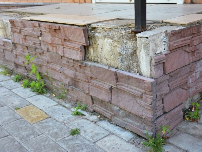 Brickmason blending new and existing brickwork with matching brick colors, mortar joints, and masonry patterns on a building