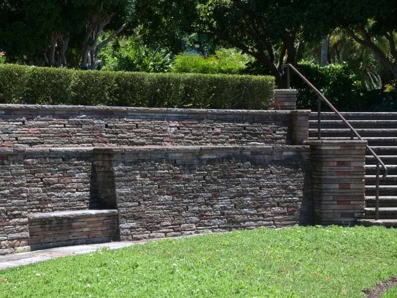 Retaining wall steps built into a tiered garden with natural stone treads, brick masonry walls, level landings, and landscaped planting beds in Birmingham.